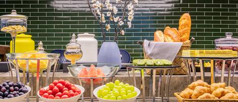 Ein Buffet mit verschiedenen Speisen, darunter Obst, Gebäck und Soßen.