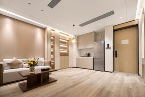 Une chambre d’hôtel moderne équipée d’un canapé, d’une table basse, d’un coin cuisine et d’une porte en bois.