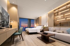 Een moderne hotelkamer met een bed, een bank, een bureau en uitzicht op de stad.