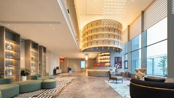 A modern lobby with a curved reception desk, seating areas, and large windows.