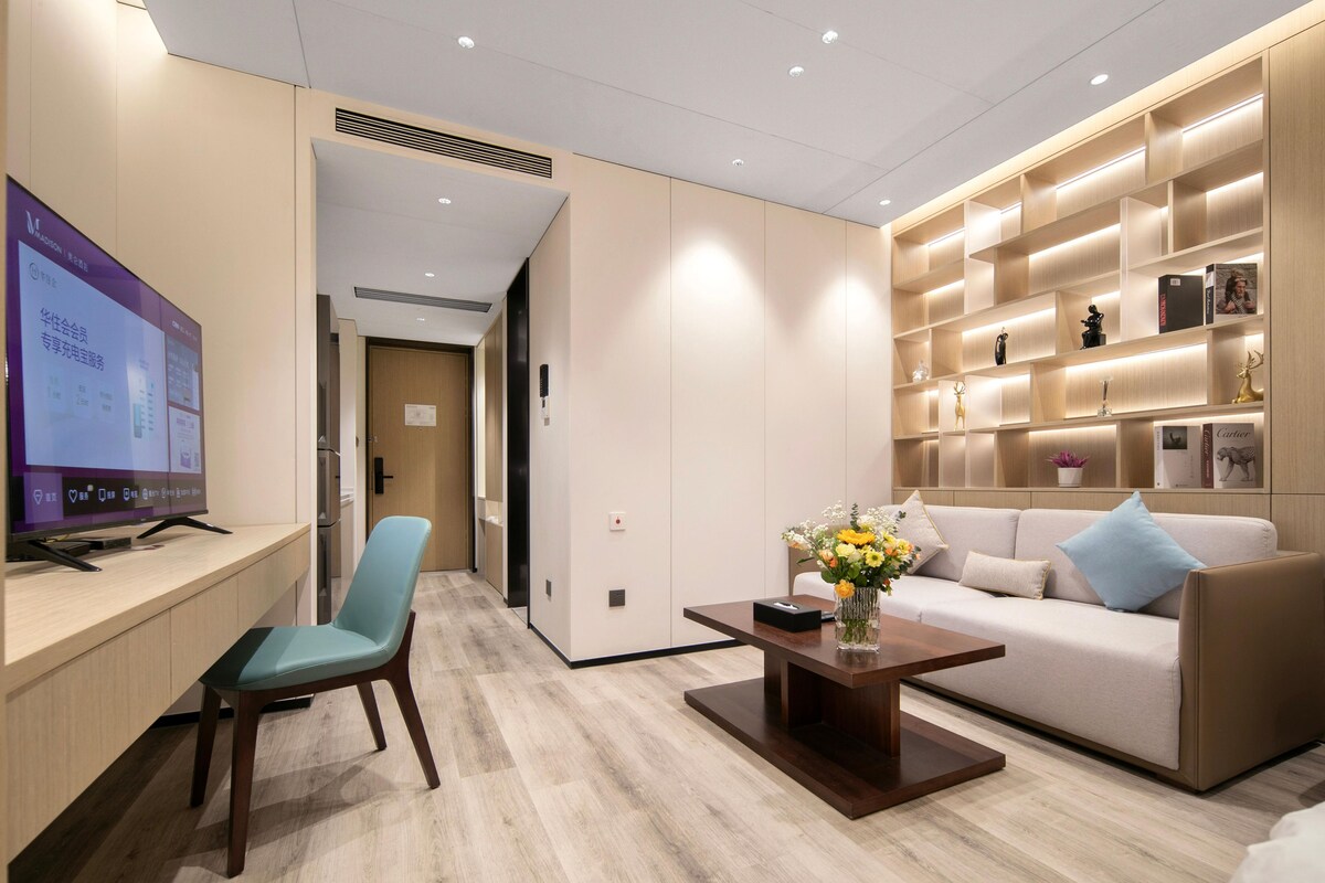 Une chambre d’hôtel moderne avec un bureau en bois, un canapé confortable, une table basse et un téléviseur.