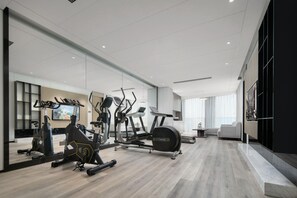 A modern home gym with exercise equipment, a large mirror, and a comfortable seating area.
