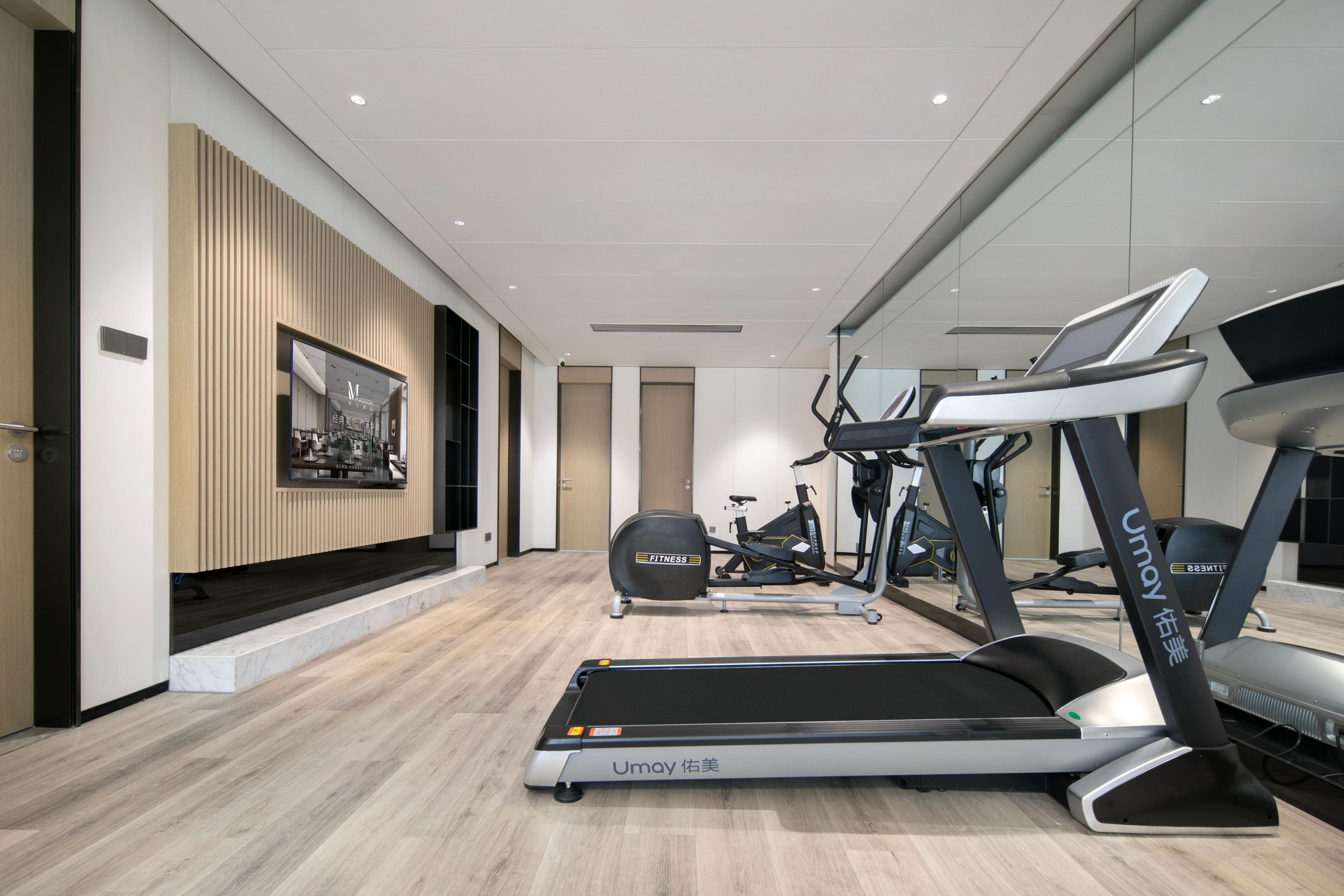 A modern gym with treadmills, stationary bikes, and elliptical machines.