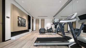 A modern gym with treadmills, stationary bikes, and elliptical machines.