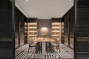 A modern dining area with a rectangular table, six chairs, and a vase of flowers.