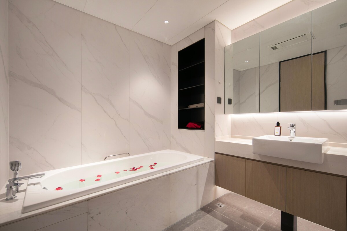 Une salle de bain moderne avec une baignoire sur pieds, un meuble-lavabo et un grand miroir.