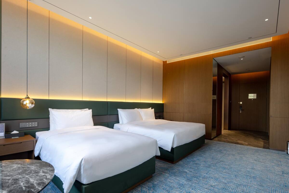 Une chambre d’hôtel avec deux lits, une table en marbre et un tapis à motifs.