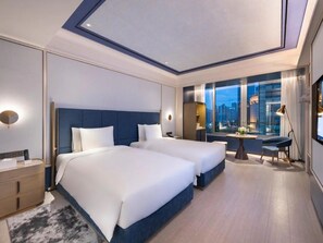 Una habitación de hotel moderna con dos camas, vista a la ciudad, un escritorio y una mesita de noche.
