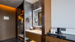 Une salle de bain moderne avec un mur en marbre, un meuble-lavabo en bois et un grand miroir.