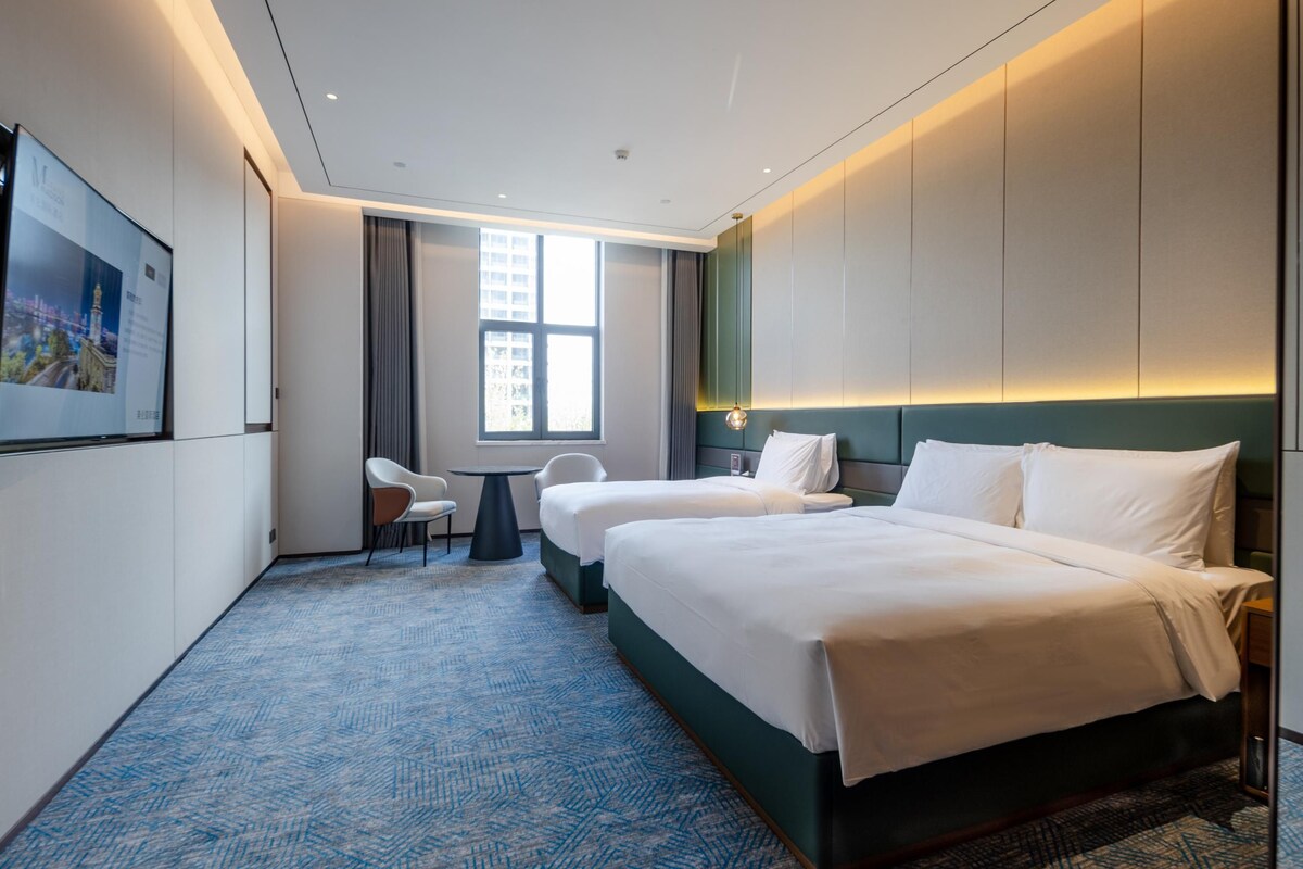 Habitación de hotel con dos camas, un escritorio y una silla.