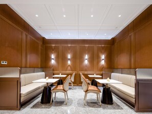 A modern hotel lobby with wooden paneling, a central seating area with sofas and chairs, and tables. - Grand Madison Hotel Tangshan Caofeidian (Tangshan)