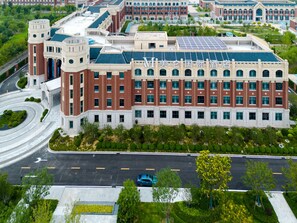 Un edificio grande de varios pisos con fachada simétrica, que presenta una sección central con varias ventanas y un techo plano con paneles solares.