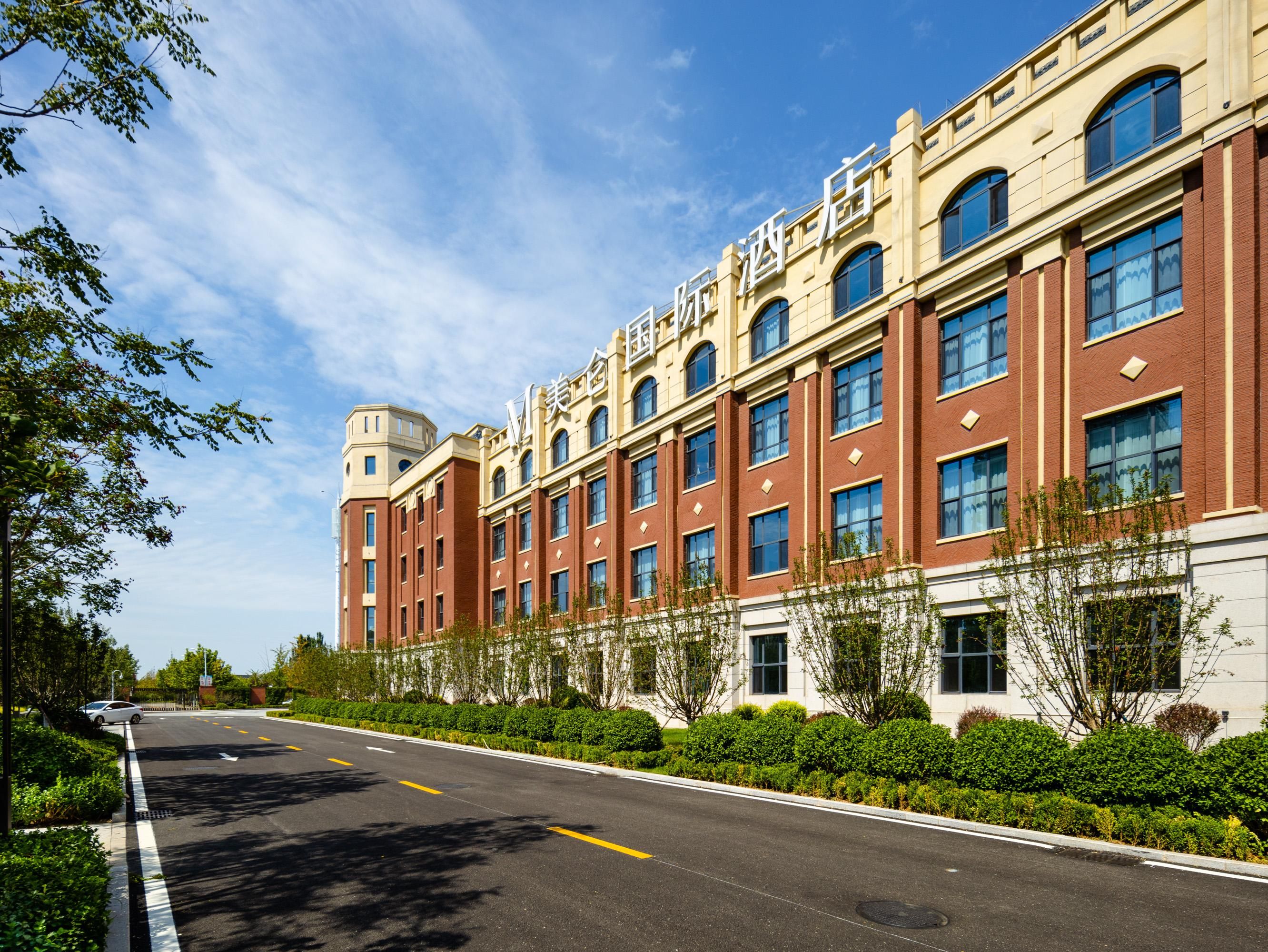 A multi-story building with a symmetrical facade, large windows, and a clear sky.