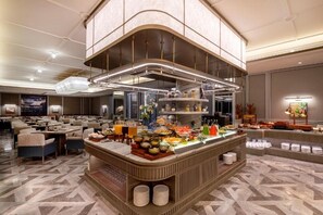 Un espace buffet proposant une variété de plats, un coin salon avec des tables et des chaises, et un design de plafond moderne.