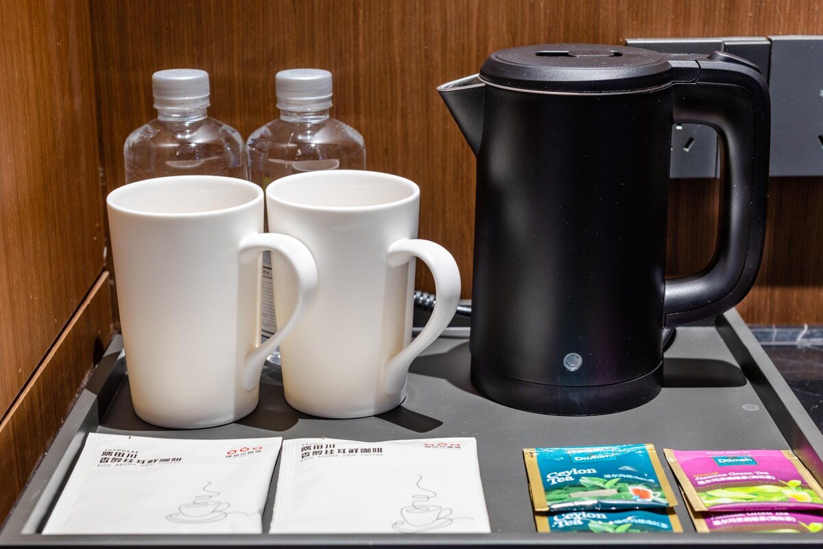 Un plat amb dues tasses blanques, una tetera elèctrica negra i sobres de te.