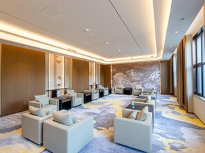 Un'ampia hall d'hotel con confortevoli zone salotto, un grande murale sulla parete e un pavimento in moquette.