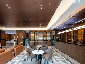 Una hall moderna di un hotel con un'area bar, posti a sedere e un pavimento in marmo.