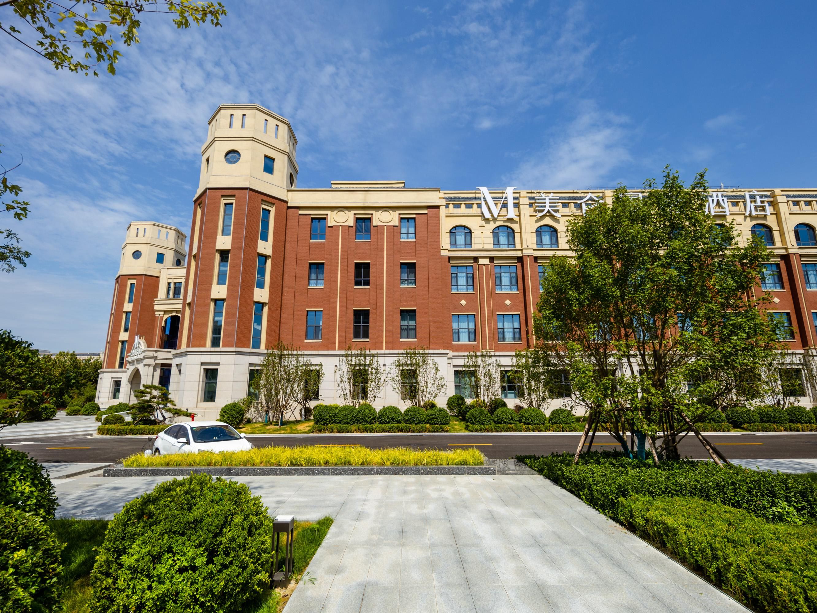 A large, multi-story building with a prominent tower, a well-maintained lawn, and a parking area.