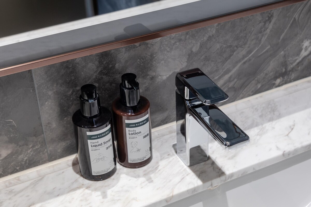 A bathroom counter with two bottles of hand soap and a hand dryer.