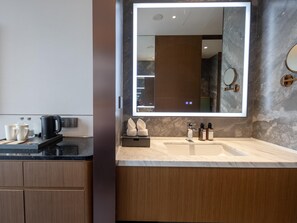 Un baño moderno con un espejo grande, un lavabo y una encimera con artículos de aseo.