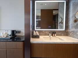 Un baño moderno con un espejo grande, un lavabo y una encimera con artículos de aseo.
