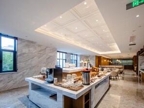 Una hall d'hotel moderna con una reception in marmo, area salotto e ampie finestre con vista sull'esterno.