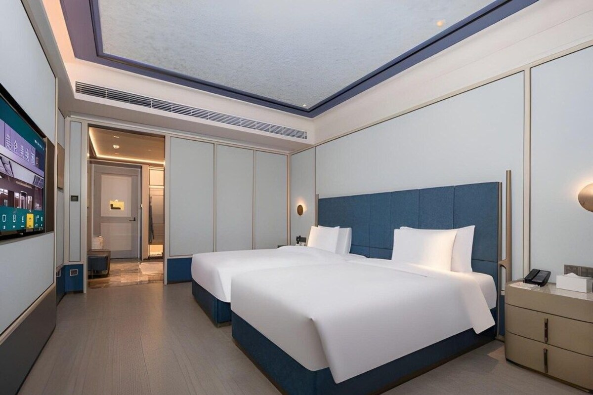 A modern hotel room with a large bed, a desk, and a television.