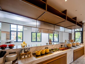 A modern kitchen with a marble countertop, various food items, and a view of the outside. - Grand Madison Hotel Tangshan Caofeidian (Tangshan)