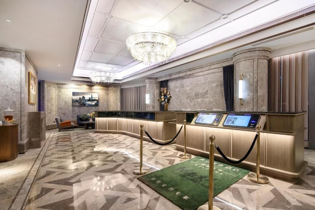 Un moderno vestíbulo de hotel con un mostrador de recepción, una araña de cristal y un suelo con diseño.