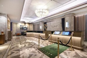 A modern hotel lobby with a reception desk, a chandelier, and a patterned floor. - Grand Madison Hotel Tangshan Caofeidian (Tangshan)