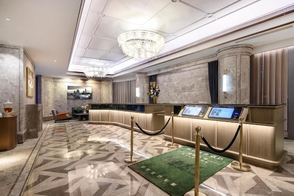 Un moderno vestíbulo de hotel con un mostrador de recepción, una araña de cristal y un suelo con diseño.