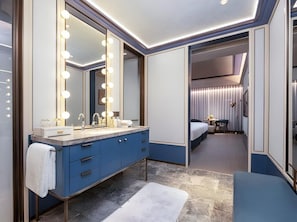 Un baño de hotel moderno con un espejo grande, tocador y una banca.