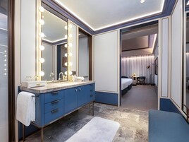 Un baño de hotel moderno con un espejo grande, tocador y una banca.