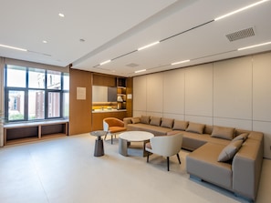 Un espace d’attente moderne doté d’une grande fenêtre, d’un canapé, de fauteuils et d’une petite table.