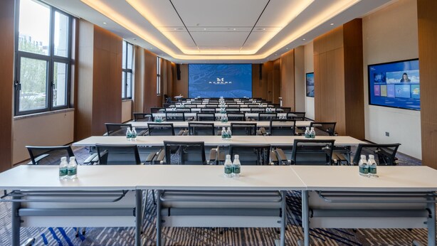 A conference room with a long table, chairs, and a large screen at the front. - Grand Madison Hotel Tangshan Caofeidian (Tangshan)