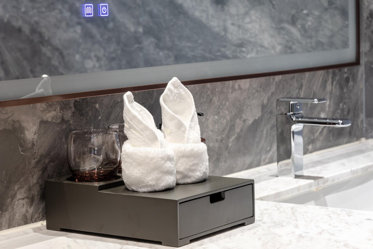 Une salle de bain moderne avec un lavabo en marbre, un sèche-serviettes et un verre de vin.