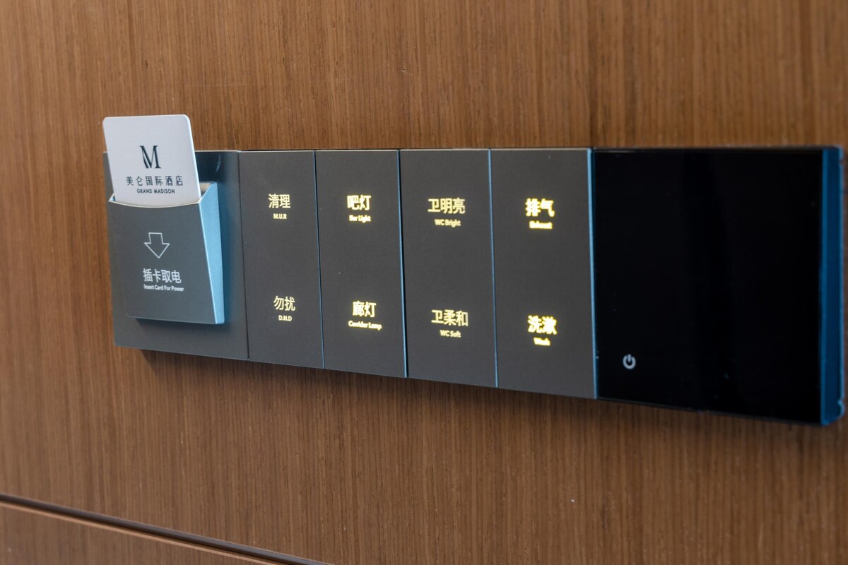 Un panneau de commande situé dans une chambre d’hôtel, doté d’un lecteur de carte et de boutons permettant de contrôler diverses fonctions de la chambre, telles que l’éclairage, la climatisation et les prises de courant.