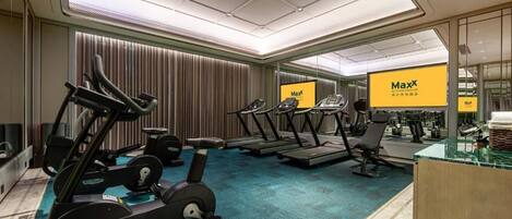 Un gimnasio con cintas de correr, bicicletas estáticas y máquinas de pesas.