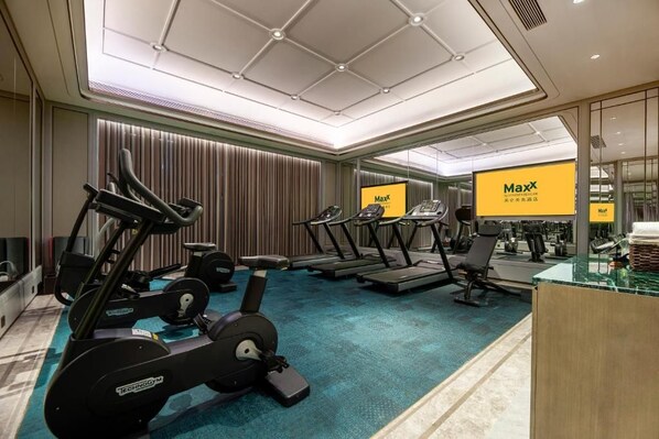 Un gimnasio con cintas de correr, bicicletas estáticas y máquinas de pesas.