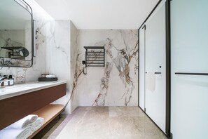 A modern bathroom with a marble wall, a vanity with a mirror, a towel rack, and a bench. - Grand Madison Hotel Nantong Tongzhou High-tech (Nantong)