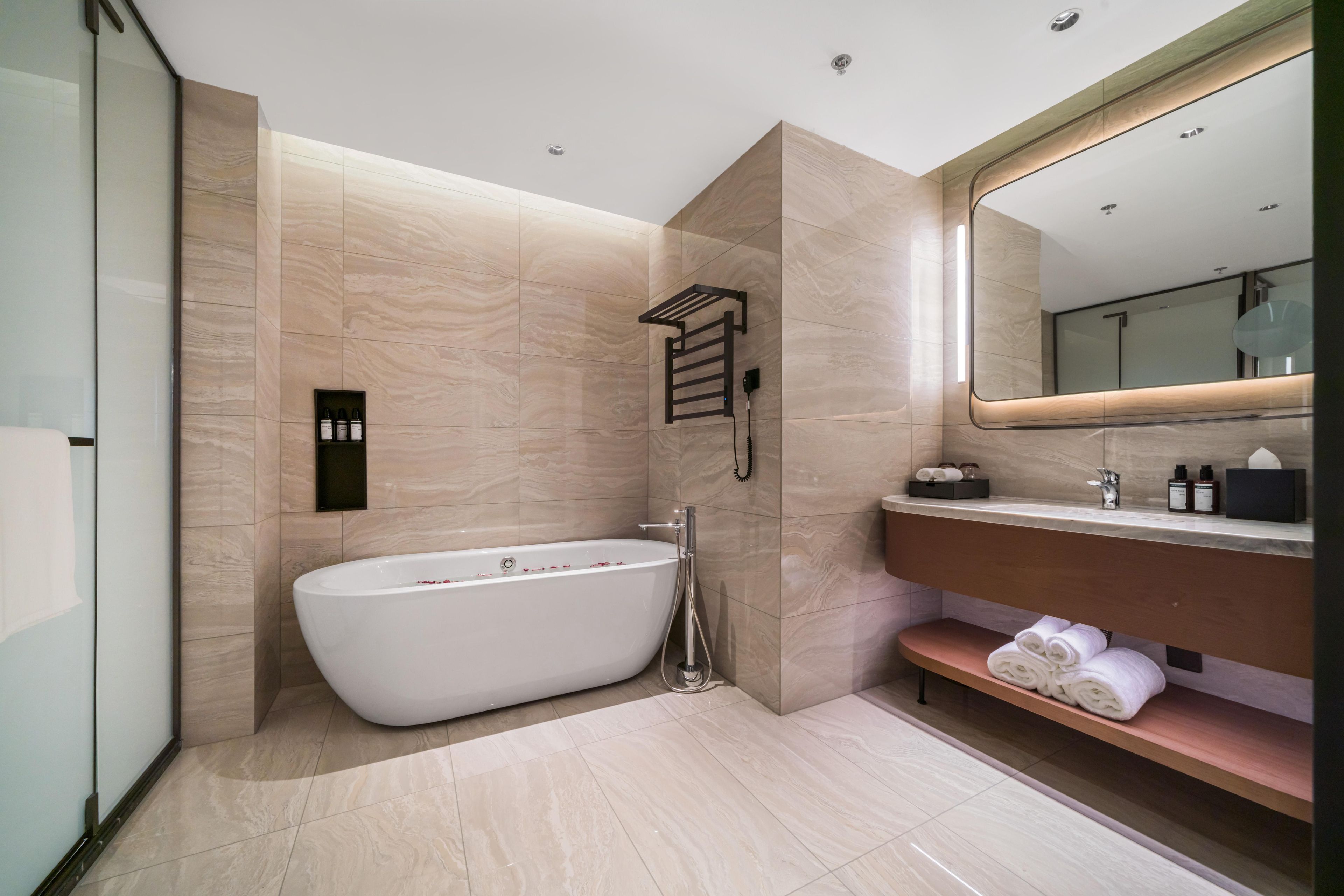 Un baño moderno con una bañera independiente, un tocador con espejo y un estante con toallas.