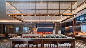 A modern hotel lobby with a buffet area, seating, and a large screen displaying content. - Grand Madison Hotel Nantong Tongzhou High-tech (Nantong)