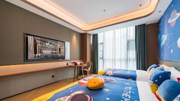 Una habitación de hotel moderna con un ventanal grande, una cama con ropa de cama temática espacial, una mesita y una silla.