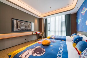 Una habitación de hotel moderna con un ventanal grande, una cama con ropa de cama temática espacial, una mesita y una silla.