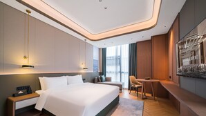 A modern hotel room with a large bed, bedside tables, a desk, and a seating area. - Grand Madison Hotel Nantong Tongzhou High-tech (Nantong)