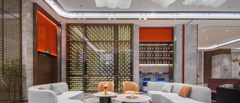 A modern lobby with a curved sofa, two round tables, and a decorative wall with vertical elements.