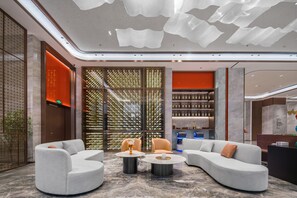A modern lobby with a curved sofa, two round tables, and a decorative wall with vertical elements.