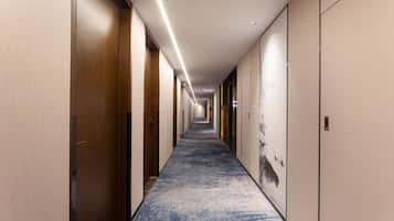 A long, narrow hallway with wooden doors on both sides, a blue carpet, and a light-colored ceiling.