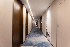 A long, narrow hallway with wooden doors on both sides, a blue carpet, and a light-colored ceiling. - Madison Hotel Hefei 2nd Affiliated Hospital (Hefei)