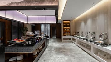 Eine moderne Hotelhalle mit einem Buffetbereich, Marmorböden und einem großen Wandbild.